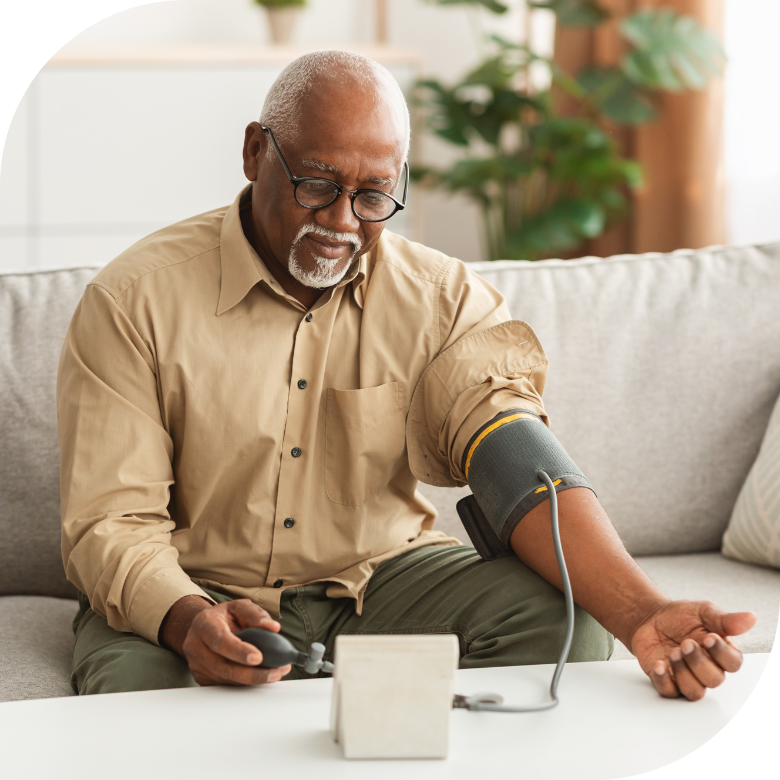 A person sits at home testing their blood pressure with an at-home monitor.