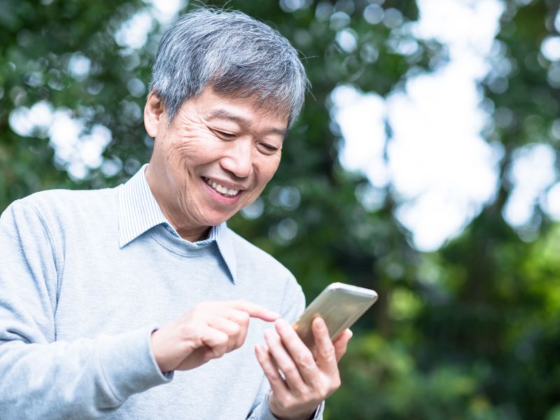 Senior person looking at mobile phone, smiling