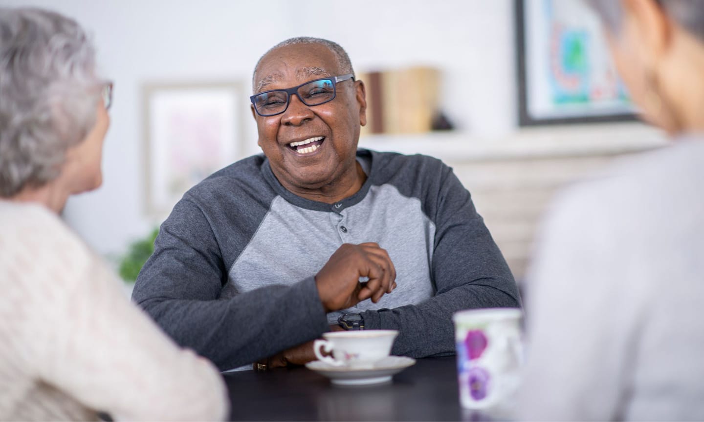 Senior person laughing with friends over tea