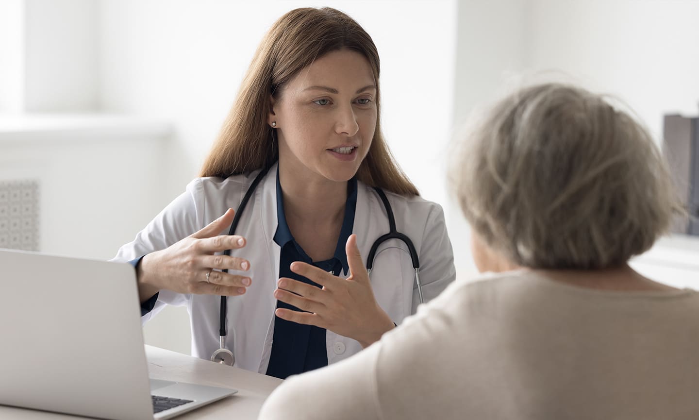 Female doctor at a desk discussing options with elderly patient